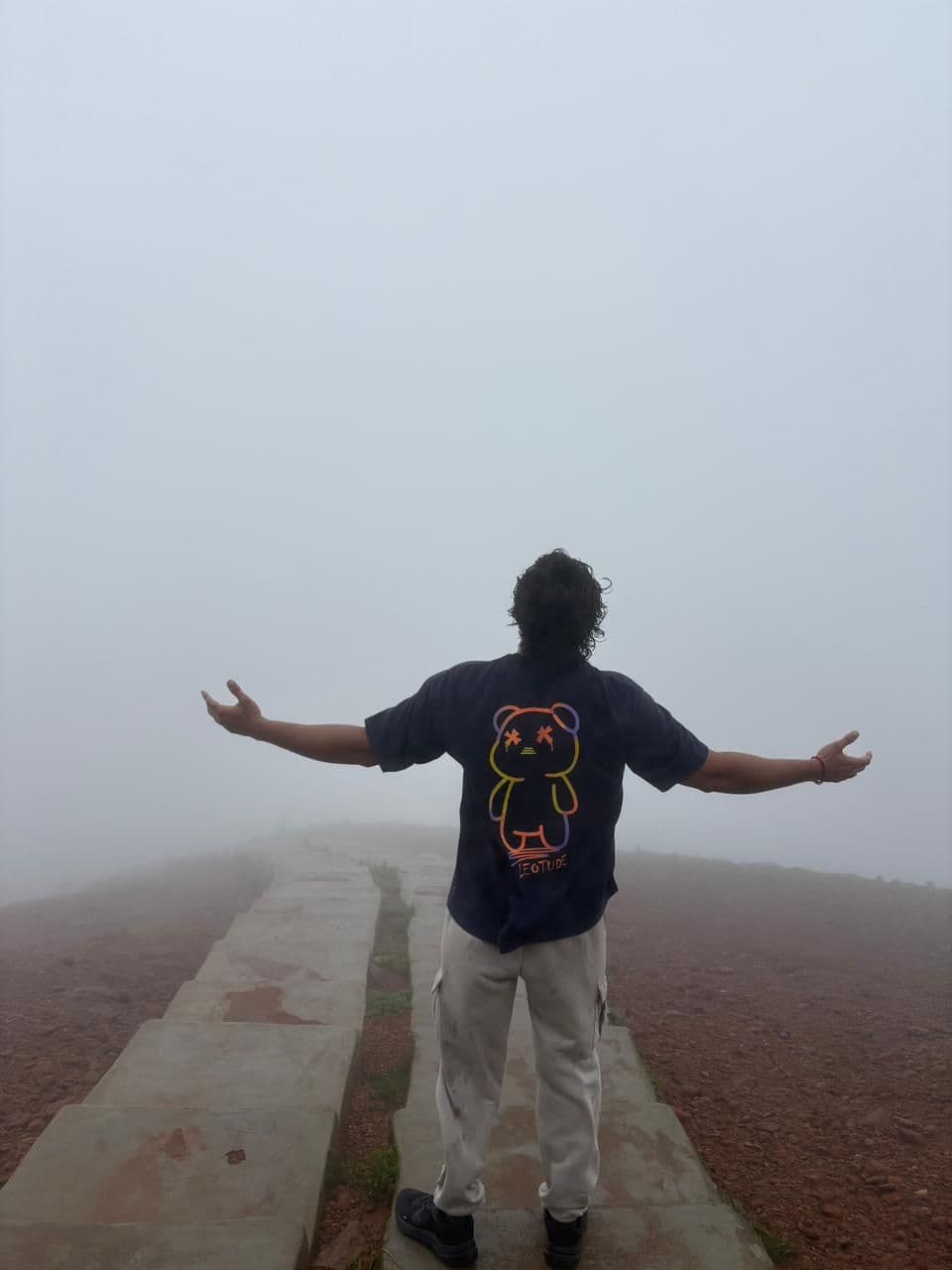 Arms open on a fog-covered summit